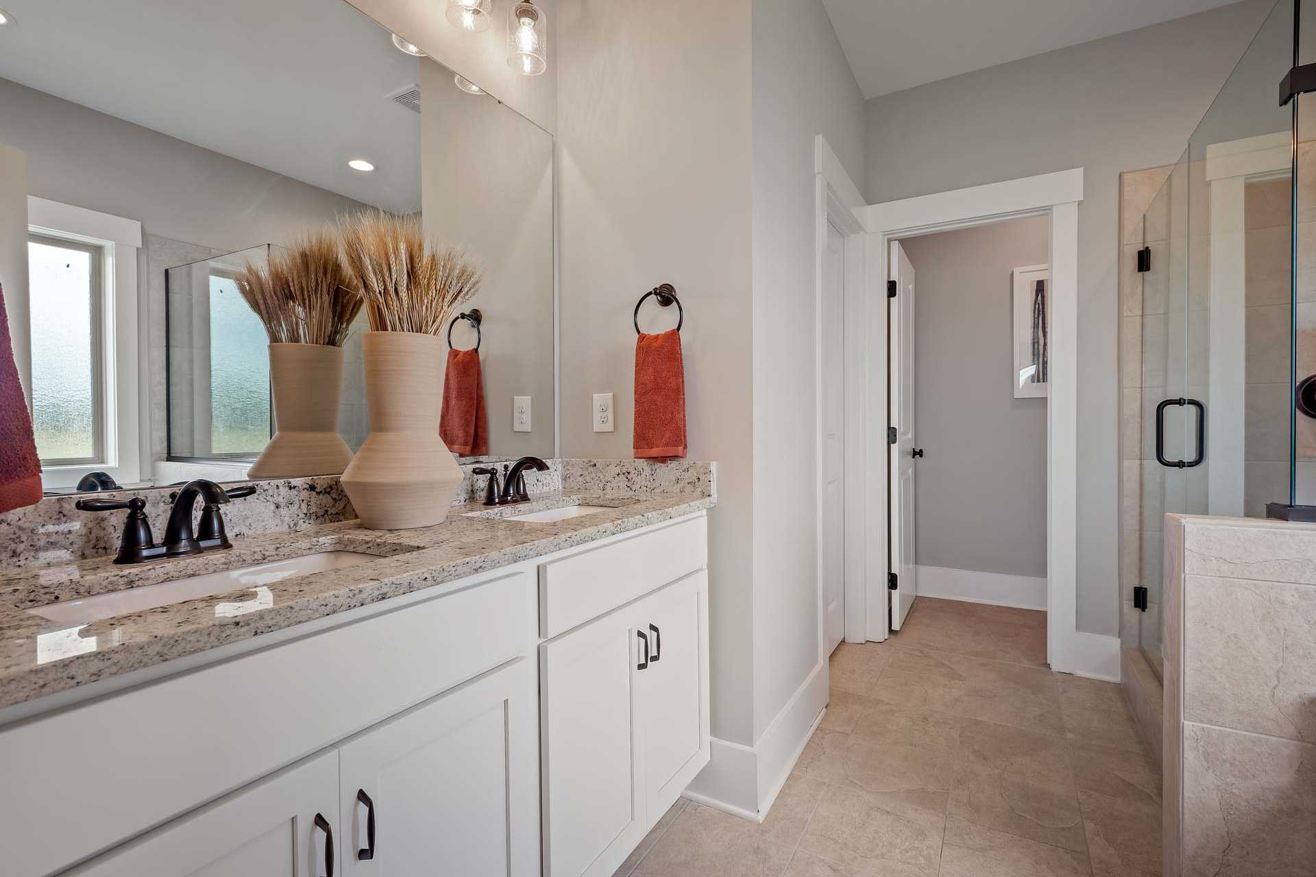 Spacious bathroom at Heritage Lakes in New Market Alabama with double vanity, white cabinets, and glass shower