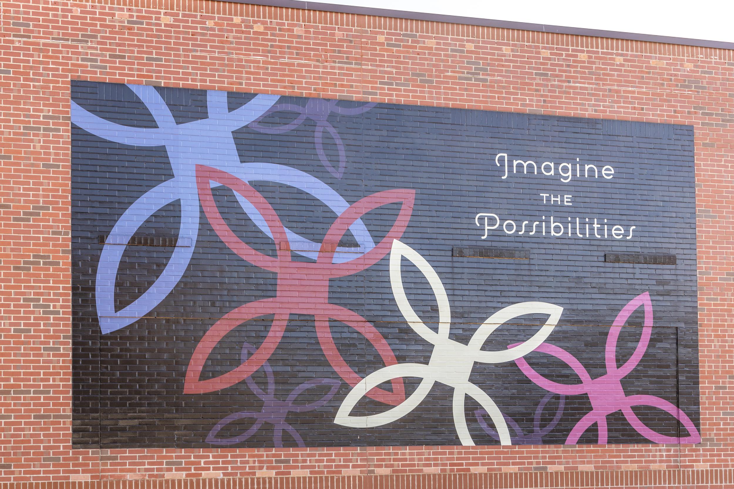 Colorful abstract floral mural on brick wall with "Imagine Possibilities" text at Sage on North Main, Wake Forest NC