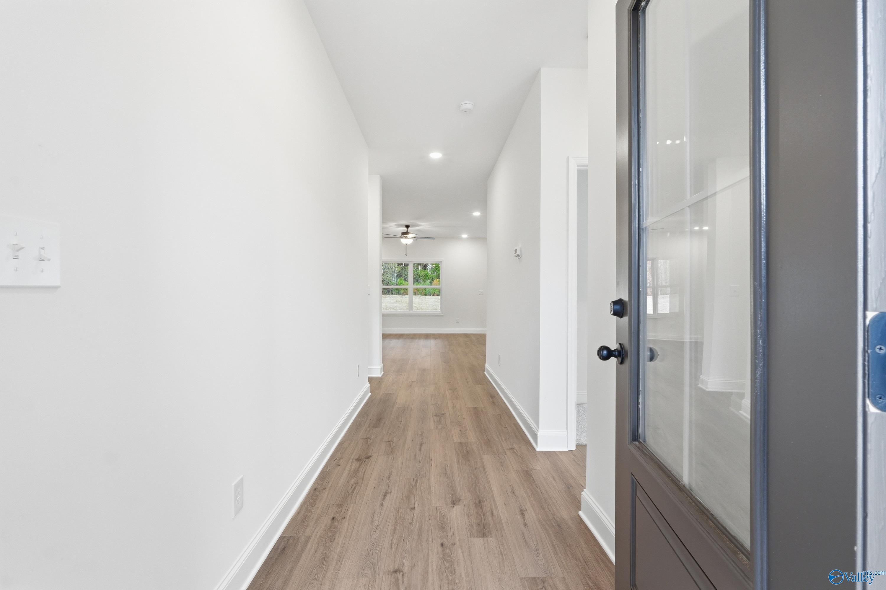 Bright entry hallway with light wood floors, white walls, and modern lighting in Davidson Homes The Asheville C, Arab, Alabama