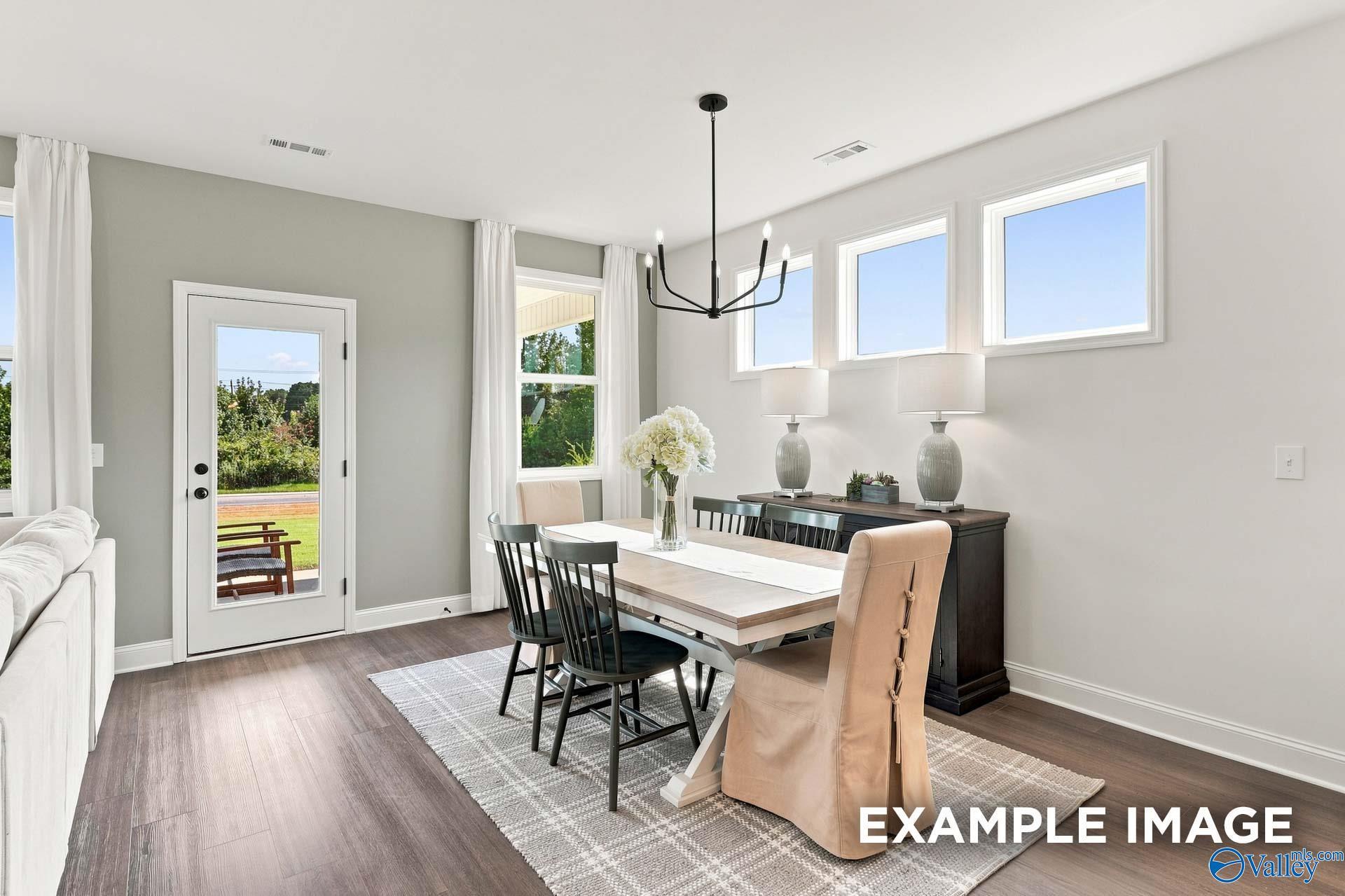Bright dining area with farmhouse table, black chandelier, and glass-paneled door in The Ashport L by Davidson Homes, Arab, Alabama