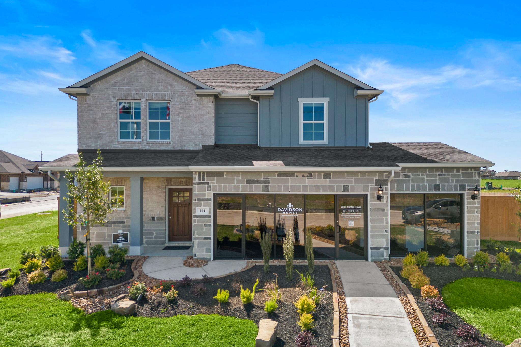 Contemporary two-story home exterior at River Ranch Meadows in Dayton Texas with stone accents, covered porch, and landscaped yard