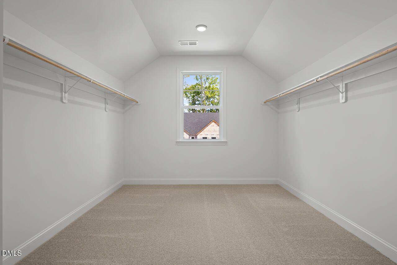 Spacious walk-in closet with dual hanging rods, vaulted ceiling, and natural light in Davidson Homes Crawford D, Wake Forest, NC