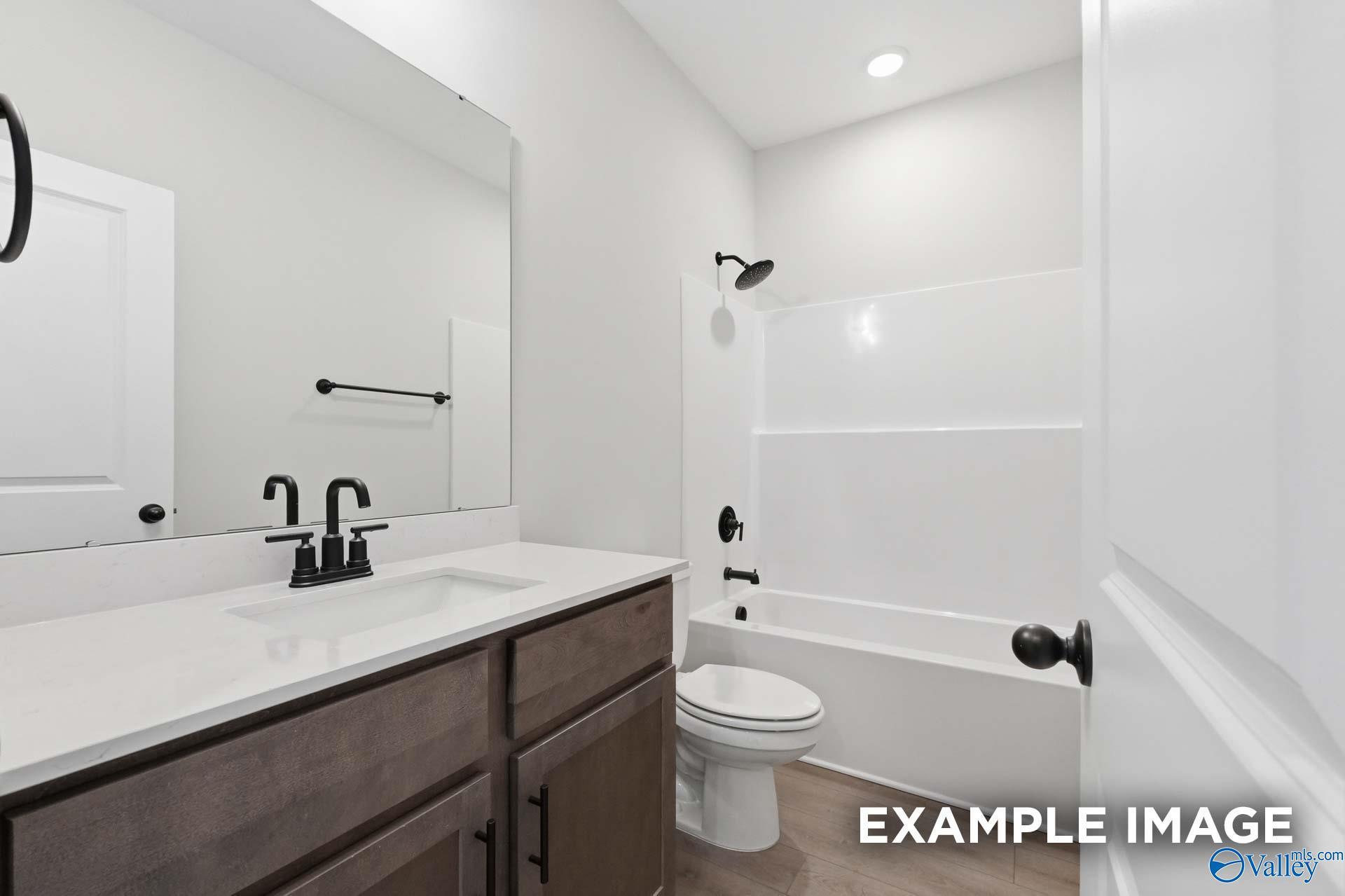 Modern bathroom with wood vanity, white quartz countertop, and matte black fixtures in The Franklin C floor plan, Athens, AL.