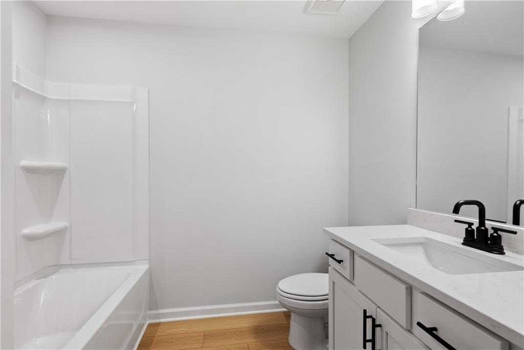 Bright white guest bathroom with tub-shower combo, single vanity, black faucet in Davidson Homes The Durant A, Emerson, Georgia
