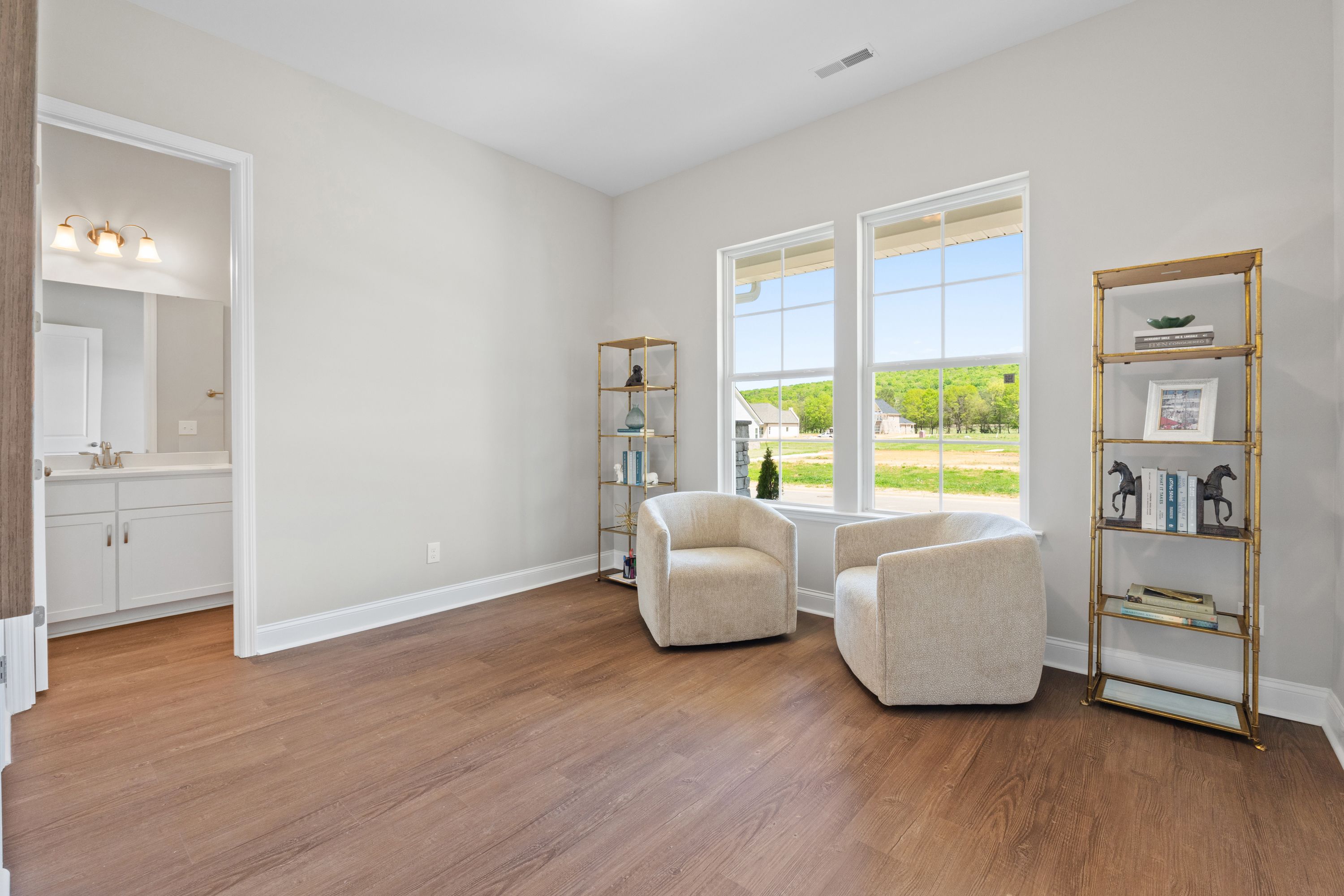 Cozy master suite sitting area in The Haven D with cream armchairs, bookshelves, hardwood floors, and en-suite bathroom