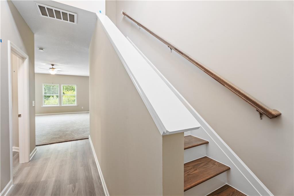Bright hallway with luxury vinyl plank floors, oak staircase, and natural light in Davidson Homes The Bartlett, Phenix City, Alabama