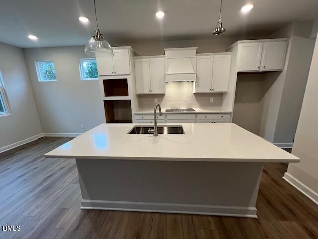 Bright white kitchen with large island sink, pendant lighting, and hardwood floors in Davidson Homes The Willow D, Lillington, NC