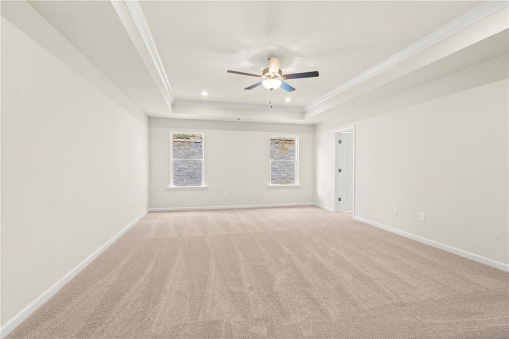 Spacious empty bedroom with ceiling fan, large windows, and beige carpet in Davidson Homes The Cary A, Kennesaw, GA