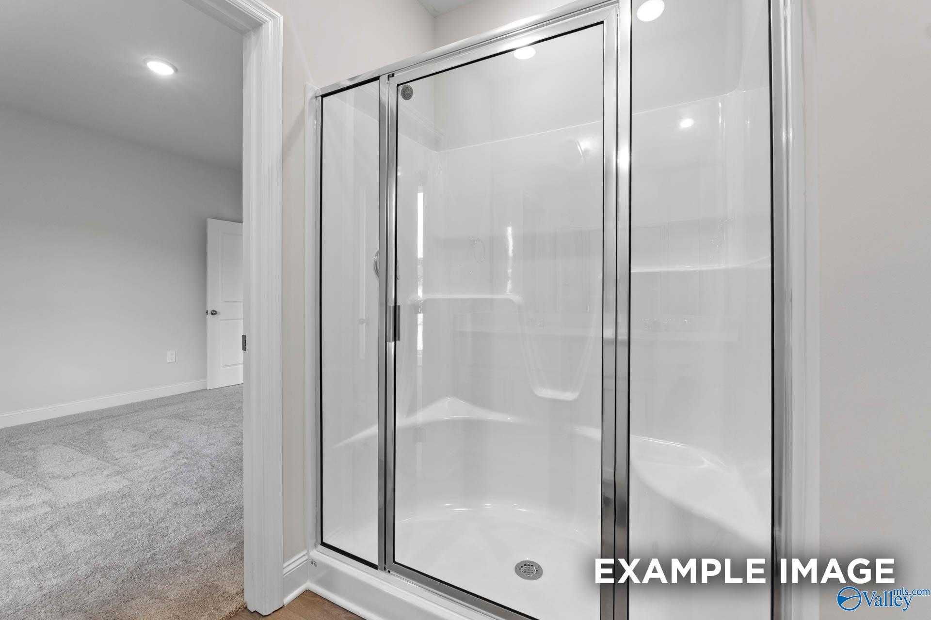 Modern glass-enclosed shower with white tiles in master bathroom, Davidson Homes The Butler, Huntsville Alabama