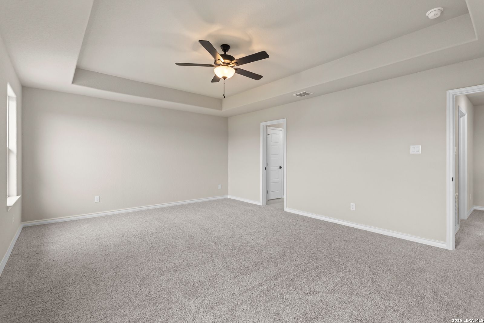 Spacious bedroom with tray ceiling and ceiling fan in The Danbury H floor plan at The Reserve at Potranco Oaks, TX.
