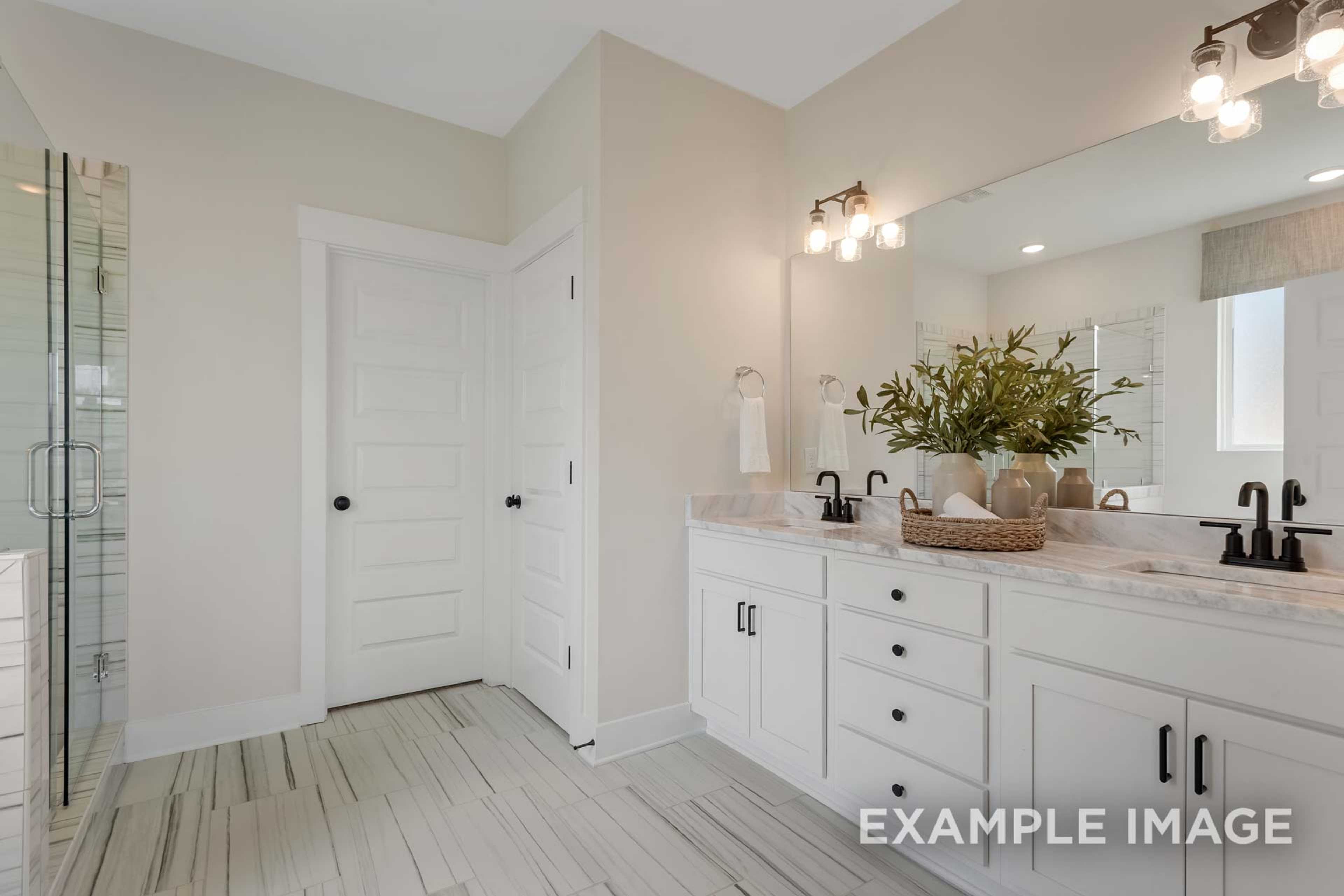 Spacious master bathroom in The Ridgeport B with double vanity, frameless glass shower, white cabinets