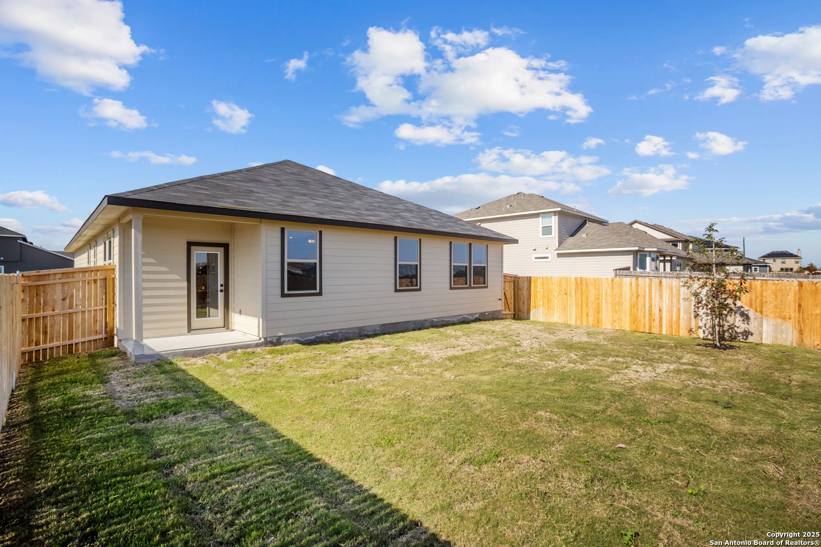 The Daphne H: beige single-story 3-bedroom home with 2-car garage, fenced grassy backyard in Hannah Heights, Seguin, Texas
