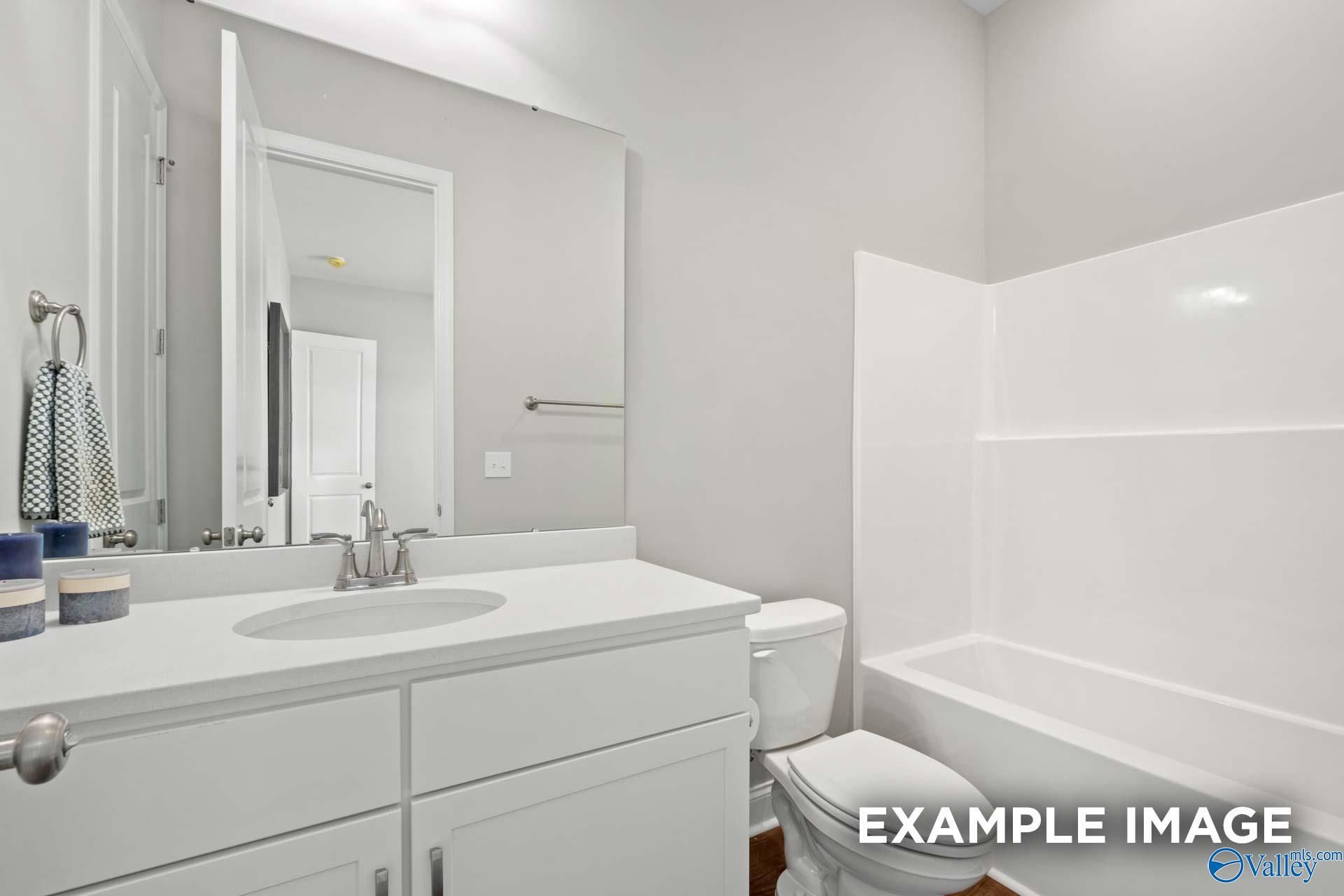 Modern guest bathroom with white vanity, oval sink, tub-shower combo, and gray walls in Evermore Homes The Haven E, Owens Cross Roads, Alabama