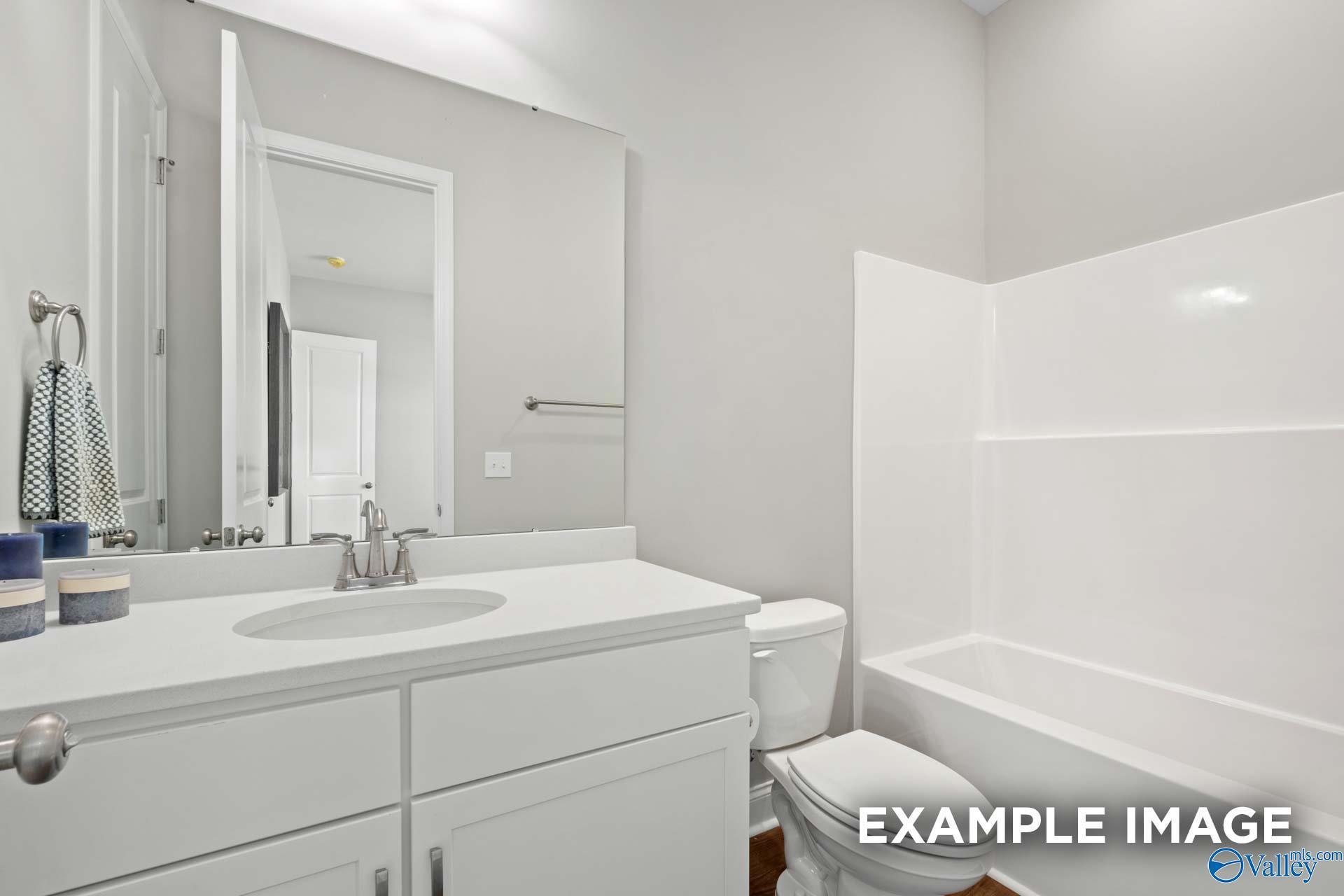 Modern guest bathroom with white vanity, oval sink, tub-shower combo, and gray walls in Evermore Homes The Haven E, Owens Cross Roads, Alabama