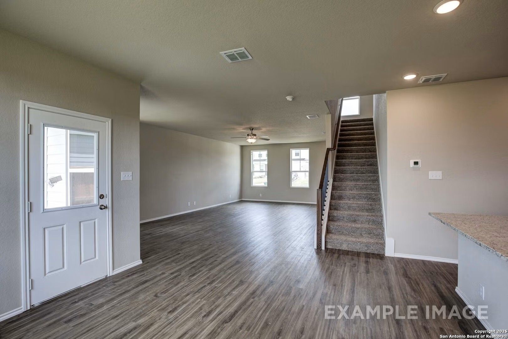 Spacious entry foyer with hardwood floors, carpeted staircase, and neutral walls in Davidson Homes The Murray K, San Antonio