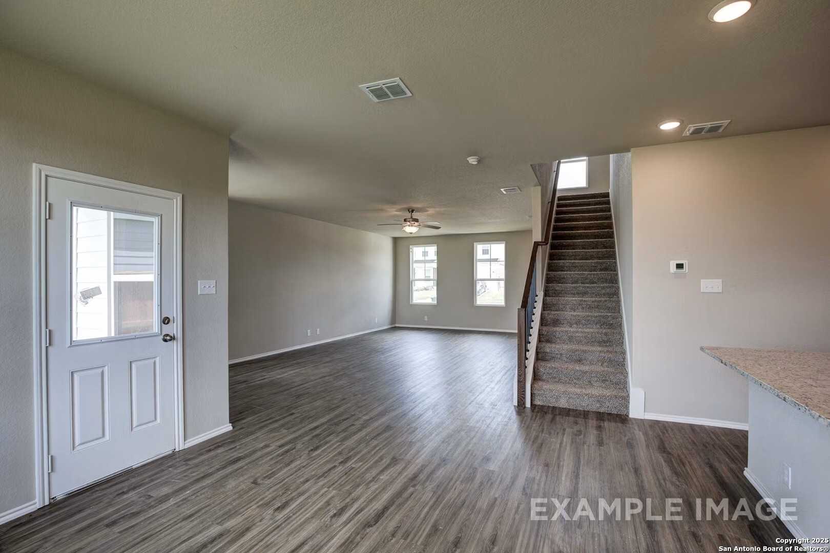 Spacious entry foyer with hardwood floors, carpeted staircase, and neutral walls in Davidson Homes The Murray K, San Antonio