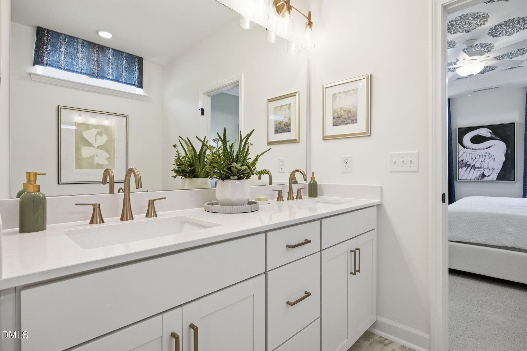 Modern double-vanity bathroom with white cabinets and gold fixtures in The Ashport M floor plan at Wendell Ridge, NC.