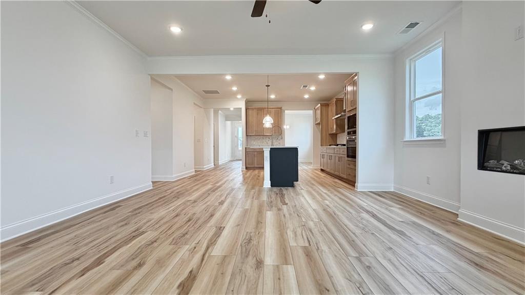Open-concept kitchen and living area with wood-style flooring in The Glenwood A at Wehunt Meadows, Hoschton, Georgia.
