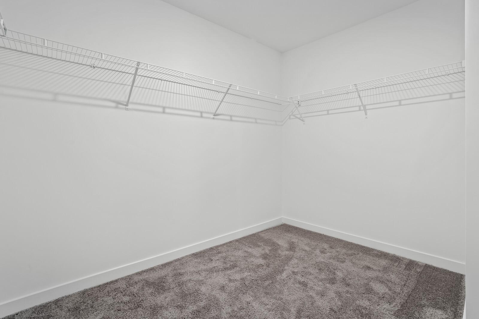 Walk-in closet with white wire shelving and plush carpet in The Logan C floor plan at Calista Farms, White House, TN.
