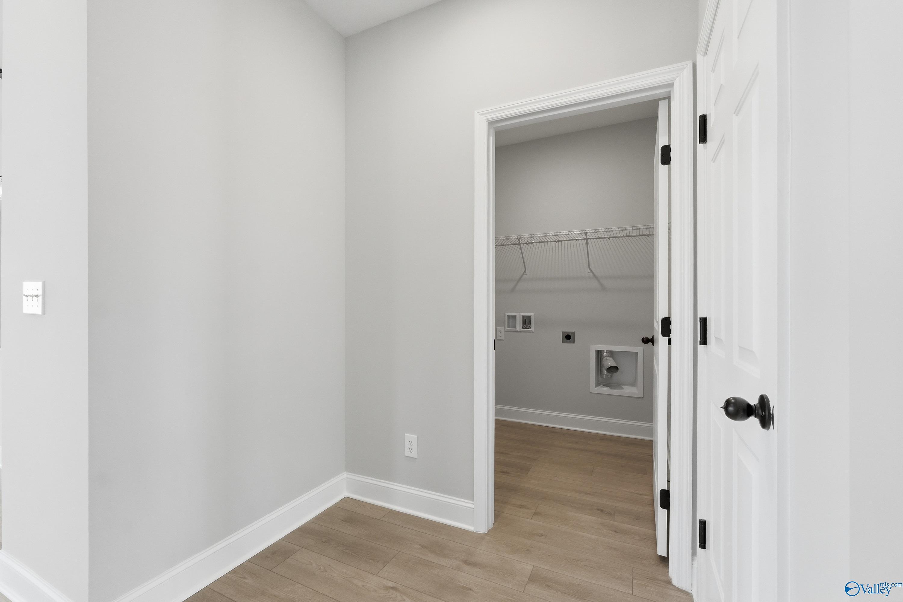 Modern laundry room with washer/dryer hookups, open shelving, hardwood floors in Davidson Homes The Franklin C, New Market, Alabama