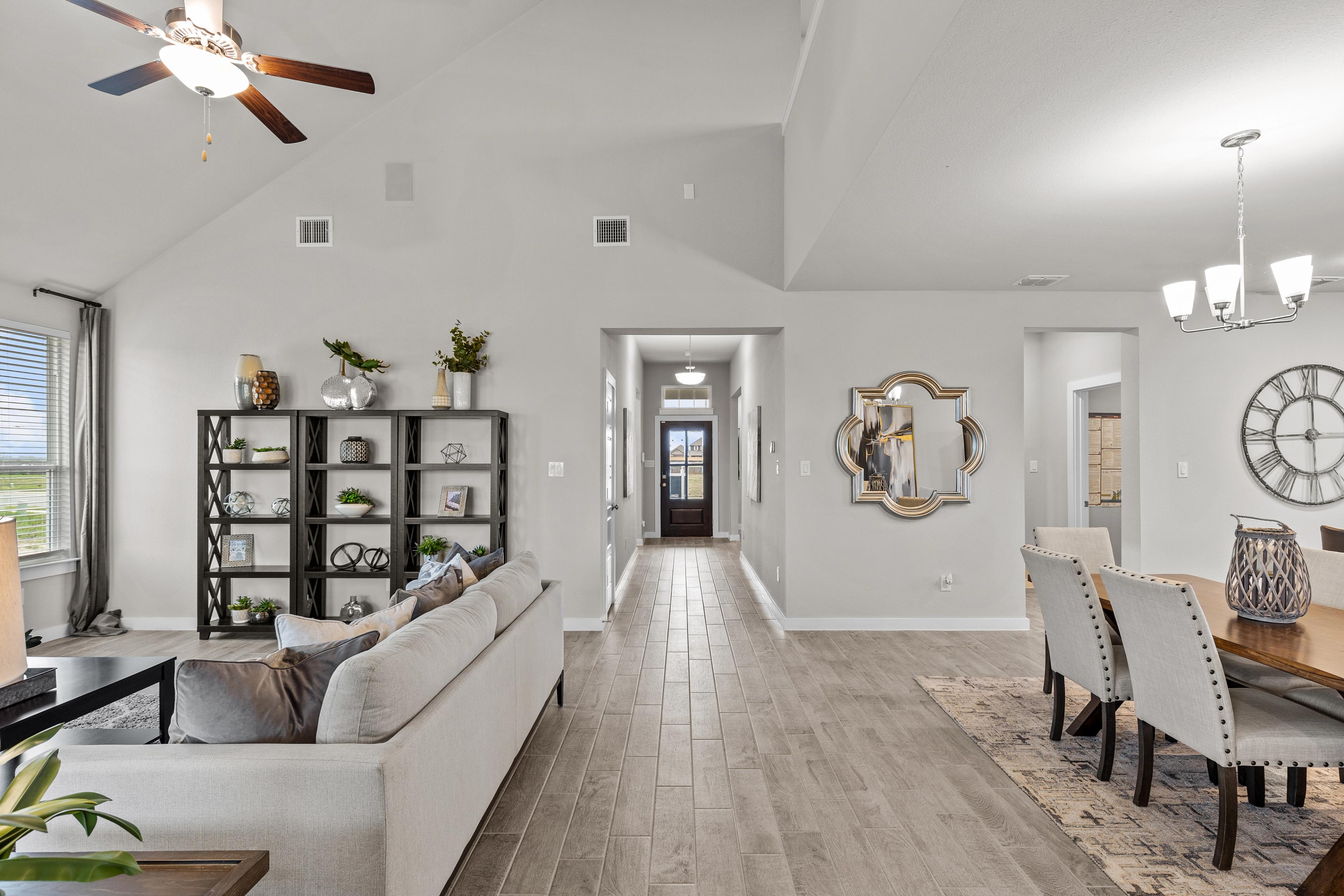 Open-concept living and dining area at Hannah Heights in Seguin TX with gray sofa, wood floors, vaulted ceiling and hallway