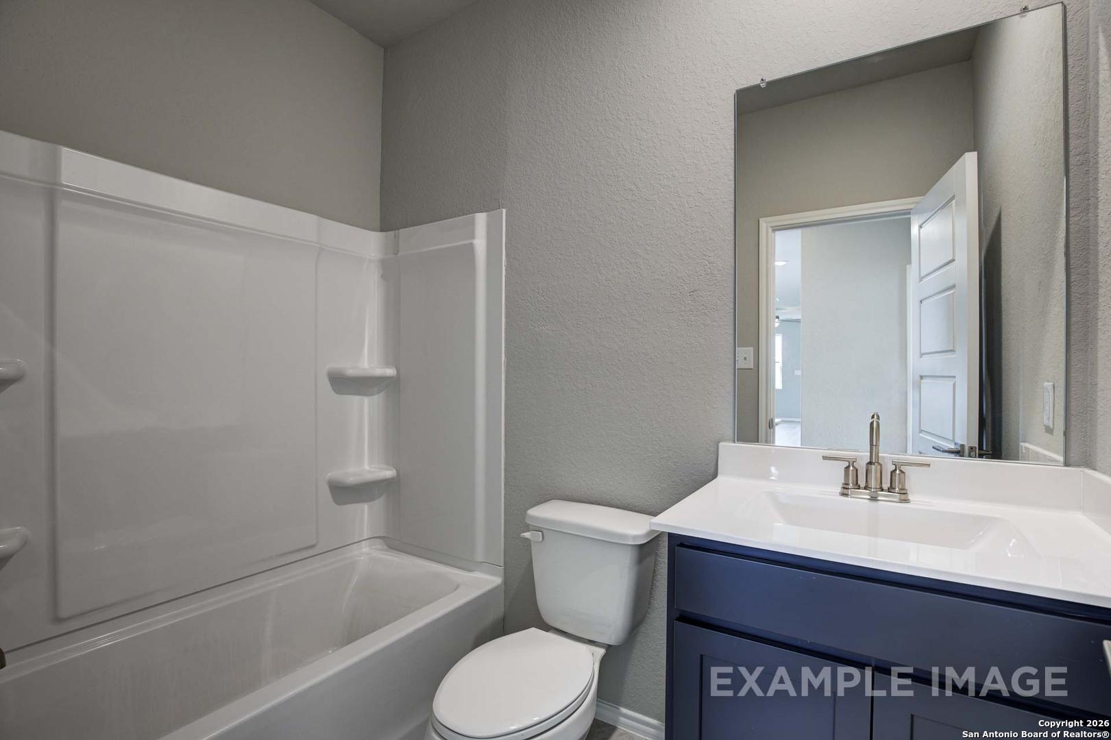 Contemporary bathroom with tub-shower combo, navy vanity, and walk-in shower in Davidson Homes The Frio C, Agave, San Antonio