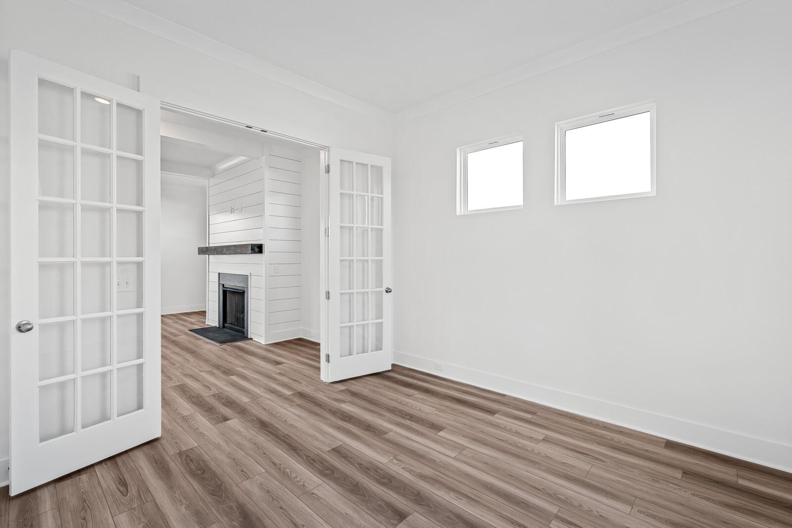 Bright formal room with open French doors to white brick fireplace, hardwood floors in The Alston A, Davidson Homes, Murfreesboro