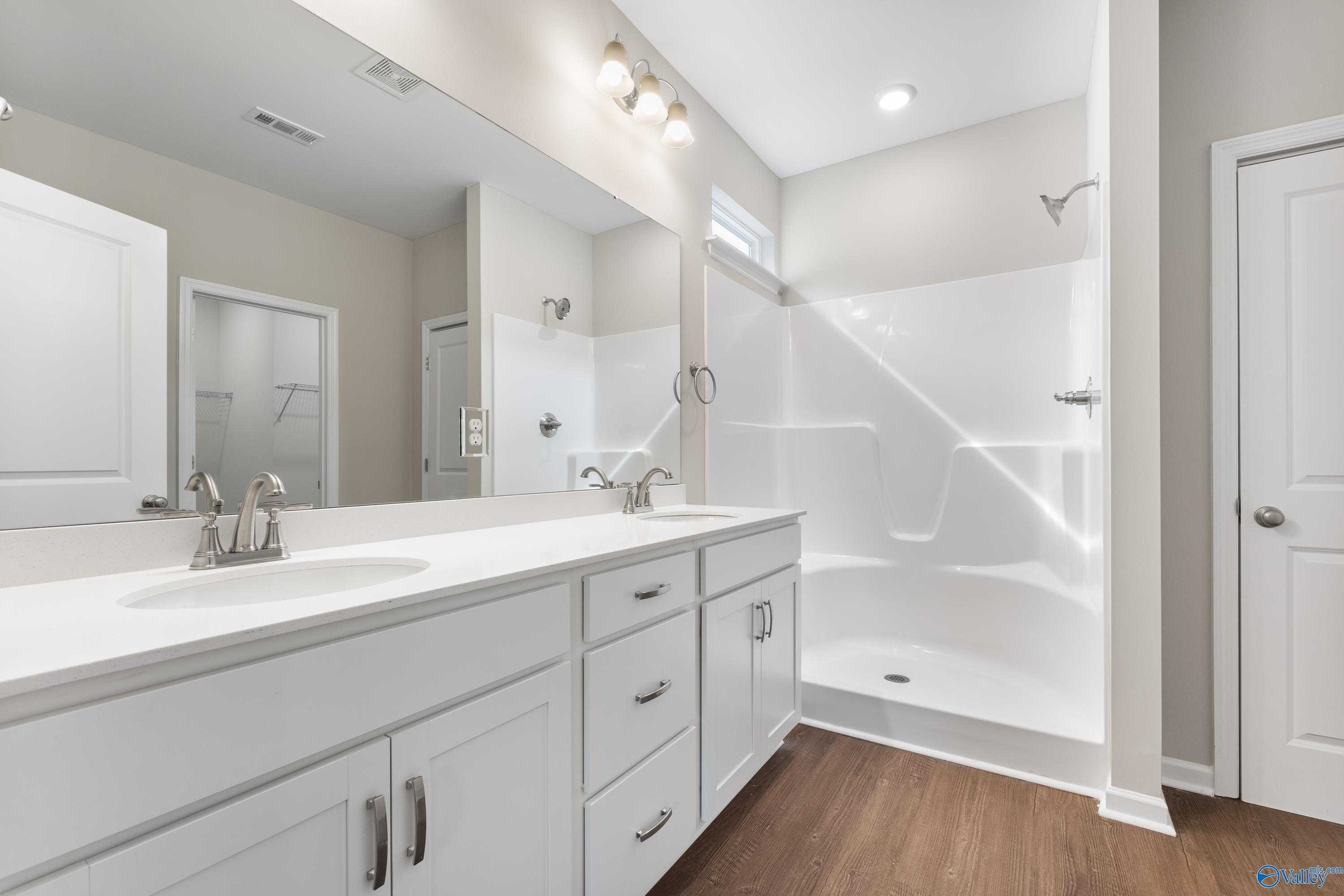 Modern master bathroom featuring double vanity, large mirrors, walk-in shower, and white cabinets in Davidson Homes The Phoenix, Fayetteville, TN
