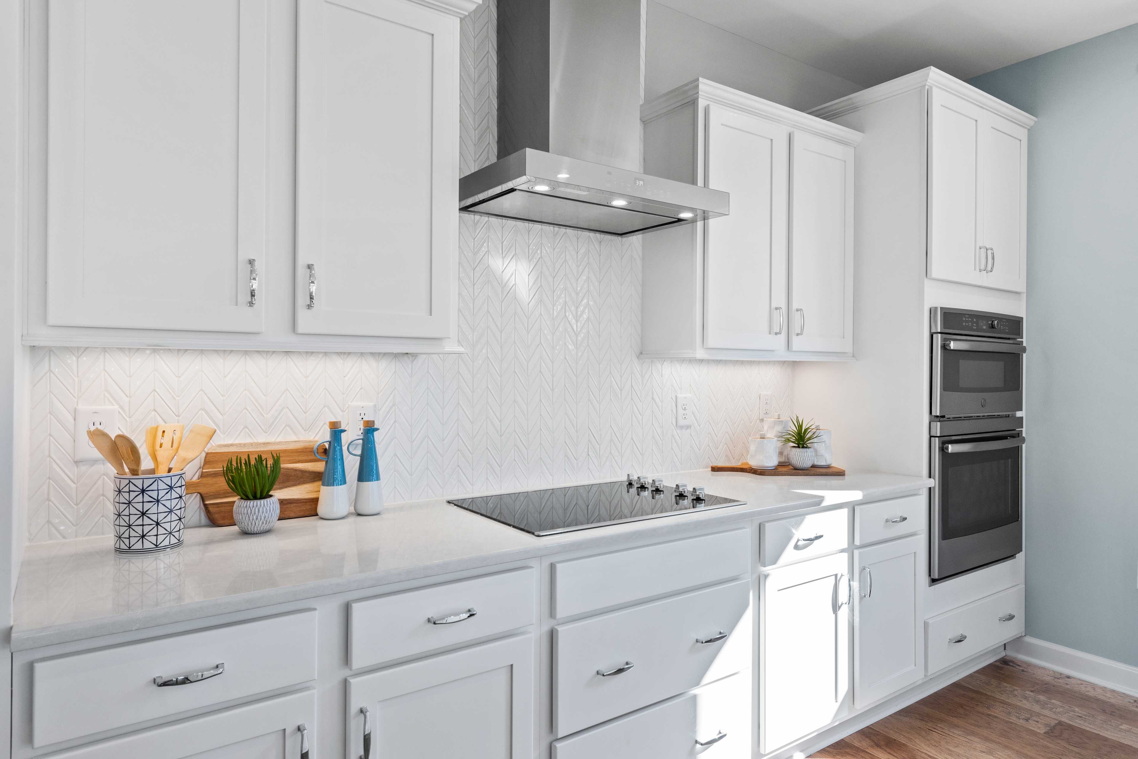 Modern kitchen with white shaker cabinets, herringbone tile backsplash, stainless steel appliances at Enclave at Belmont, Belmont NC by Davidson Homes