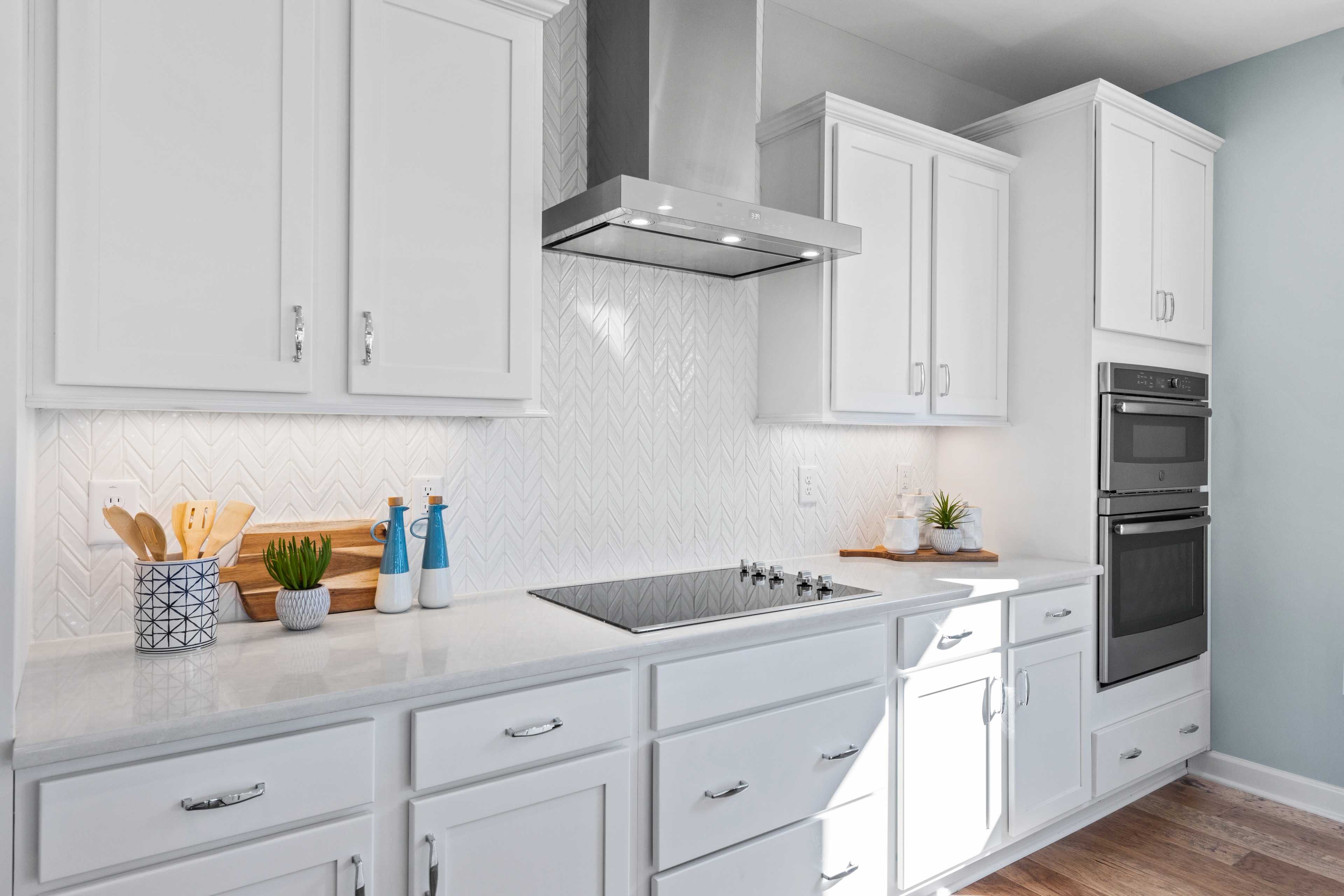 Modern kitchen with white shaker cabinets, herringbone tile backsplash, stainless steel appliances at Enclave at Belmont, Belmont NC by Davidson Homes