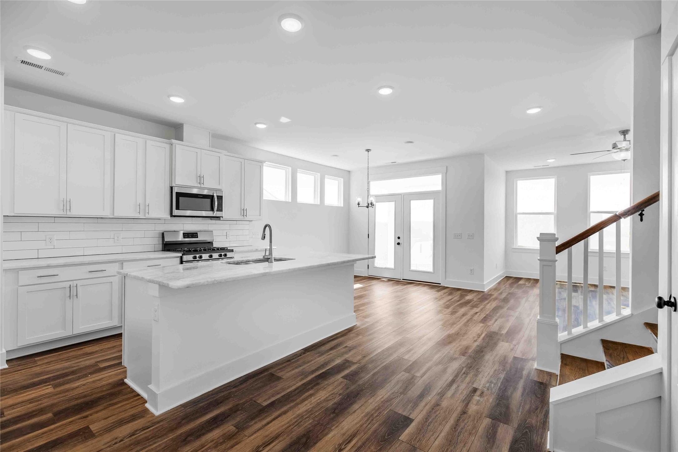 Modern open-concept kitchen with white cabinets and island in The Ash O floor plan at Heartland, Texas.