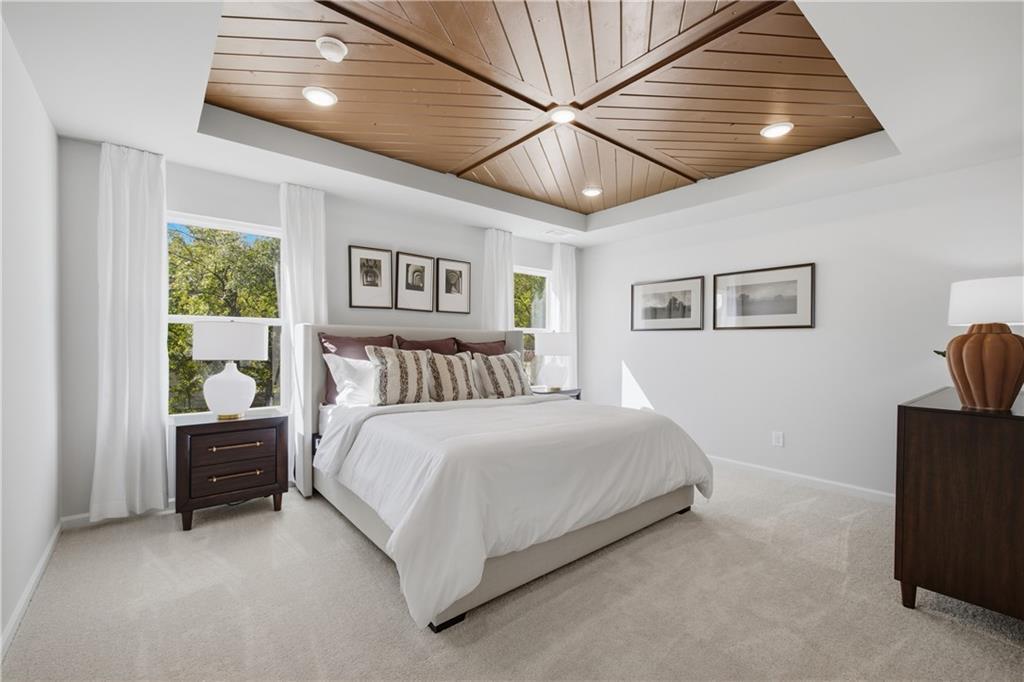 Elegant primary bedroom with wood plank ceiling detail, plush king bed, and natural light in The Sinclair B, Cartersville, Georgia