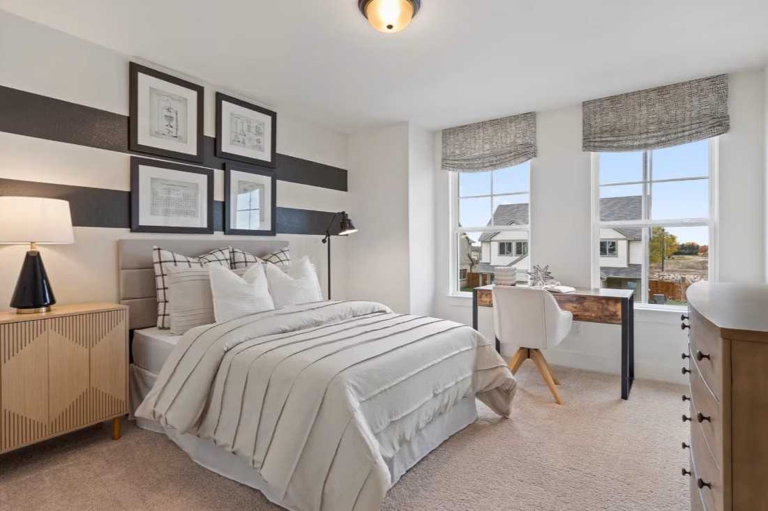 Cozy bedroom with plush bed, modern desk, large windows and abstract art in Davidson Homes The Wake C, Wylie Texas
