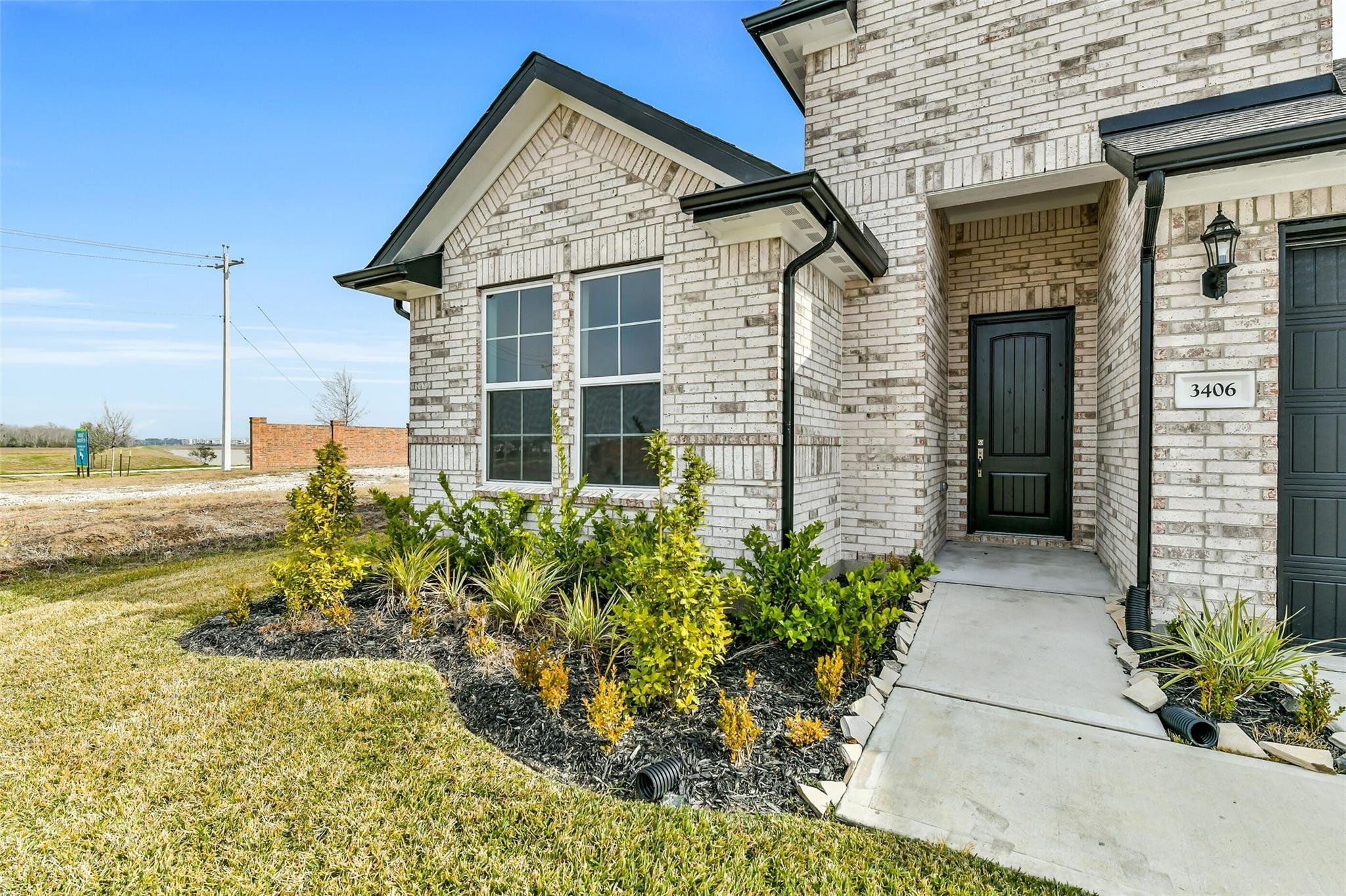 Modern brick facade of 4-bedroom Davidson Homes The George A in Lago Mar, Texas City, Texas, featuring 3-car garage and lush front landscaping