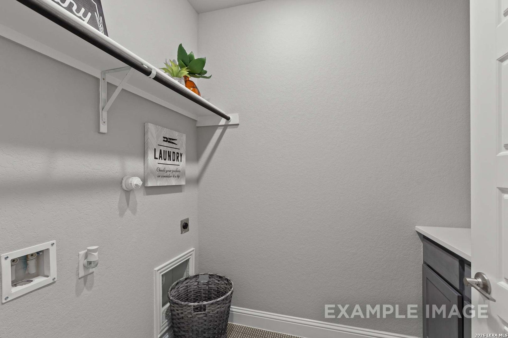 Laundry room with storage shelf and wicker basket in The Garner C floor plan at The Reserve at Potranco Oaks, Texas.