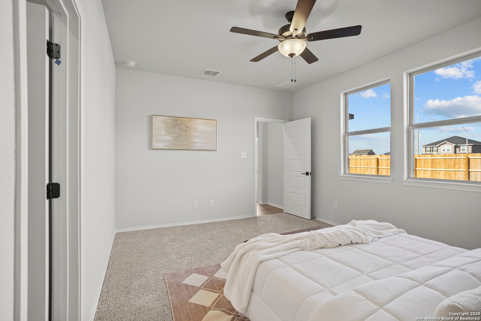 Cozy bedroom with ceiling fan, large windows, and backyard view in Davidson Homes The Douglas C, Seguin, Texas