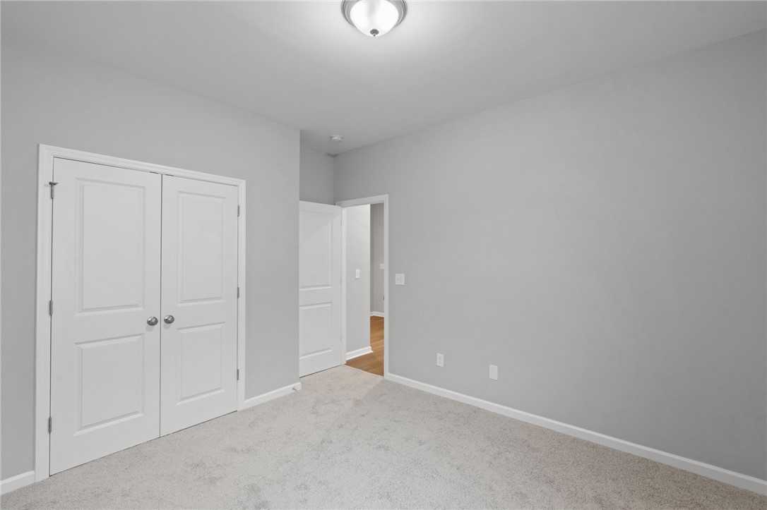Light gray bedroom with white double closet doors, open bath entry, carpet floor in Davidson Homes The Luna B, Opelika AL