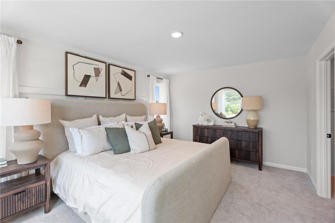 Bright primary bedroom with upholstered bed and wood dressers in Davidson Homes The Stella B, Anderson Lakes, Opelika, Alabama