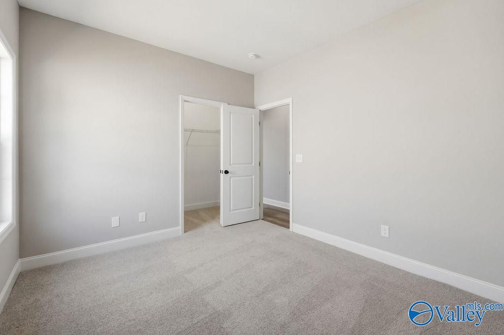 Bright bedroom with neutral carpet and walk-in closet in The Rockford floor plan at Cain Park, Hartselle, Alabama.