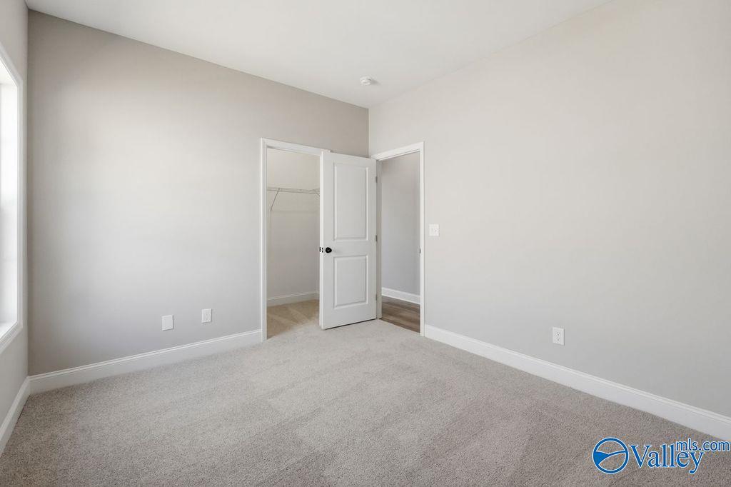 Bright bedroom with neutral carpet and walk-in closet in The Rockford floor plan at Cain Park, Hartselle, Alabama.