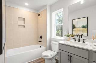 Spacious master bathroom in The Washington H townhome with tiled shower, soaking tub, double vanity, and natural light