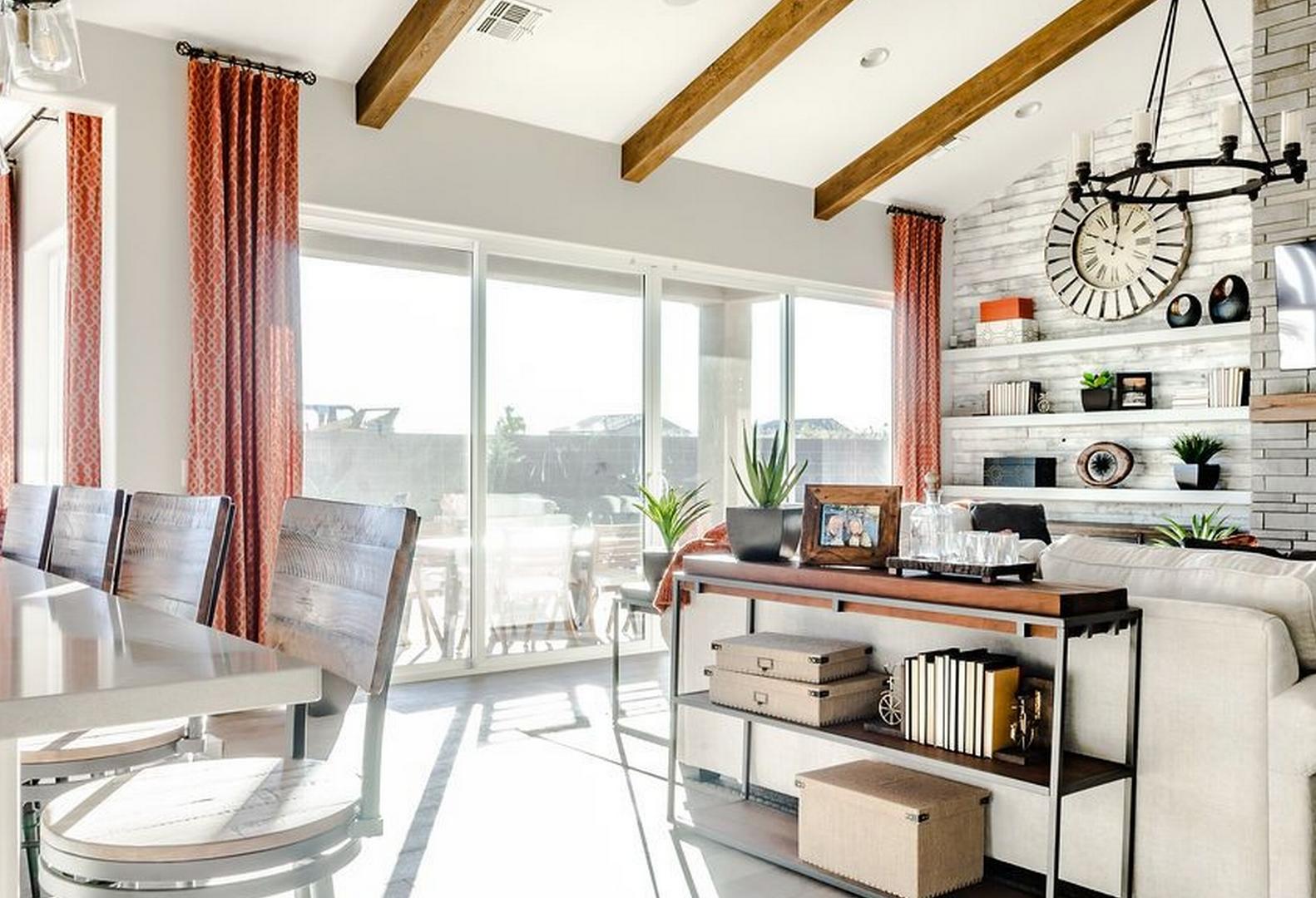Open-concept living and dining area in The Monarch home design by Evermore Homes, Prescott Valley, featuring exposed beams, stone fireplace, and large windows