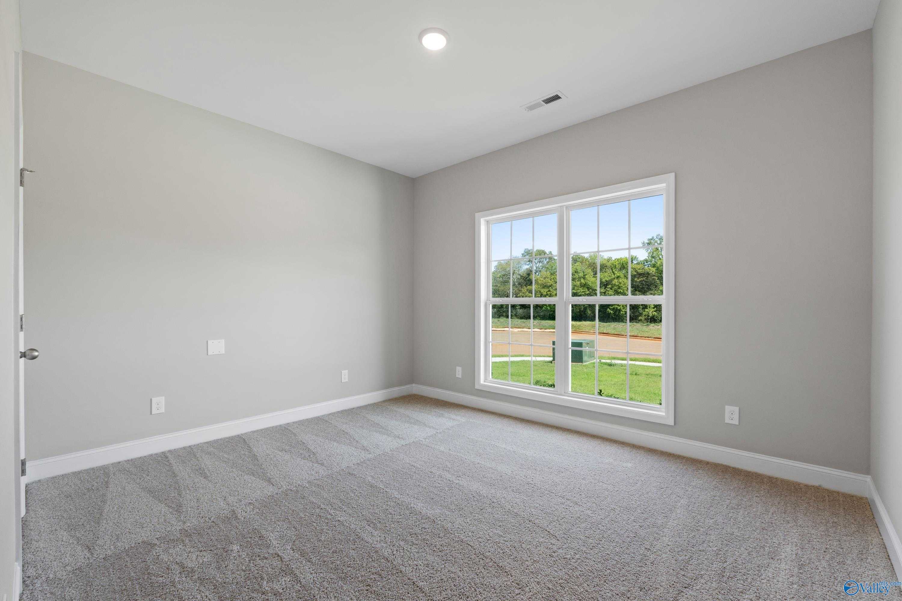 Bright empty bedroom with large window overlooking wooded yard in The Daphne C, Davidson Homes, Athens, AL