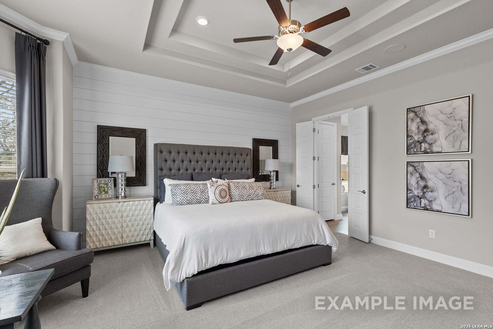 Primary bedroom with shiplap accent wall and tray ceiling in The Garner C floor plan at The Reserve at Potranco Oaks.