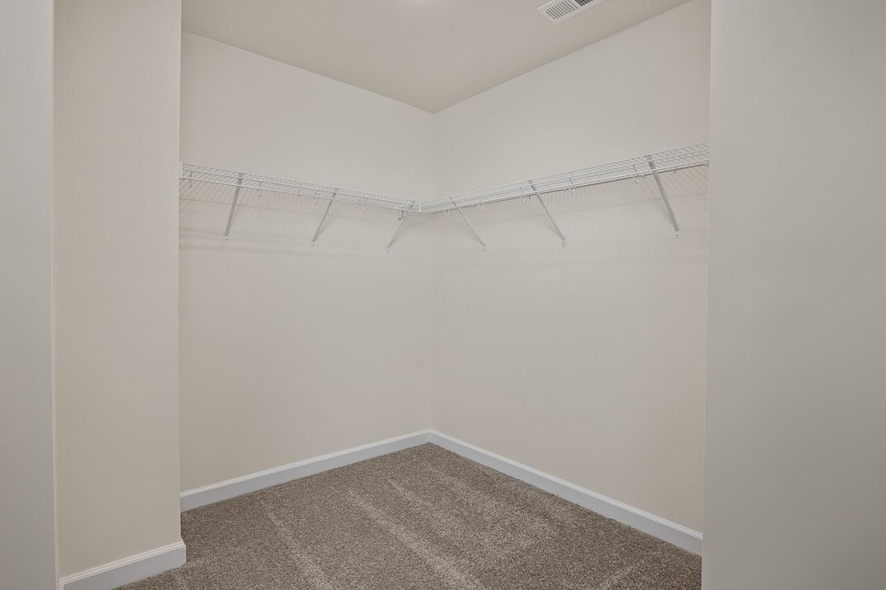 Spacious walk-in closet at Gregory Village Townhomes in Lillington, NC with wire shelving and beige carpet