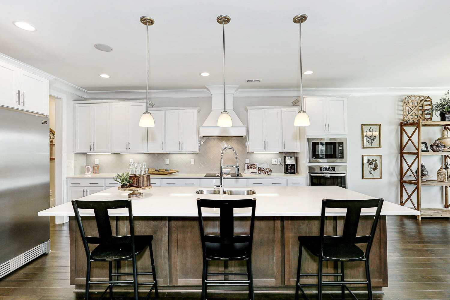 Spacious kitchen in The Finleigh by Davidson Homes featuring white shaker cabinets, large quartz island, and pendant lights