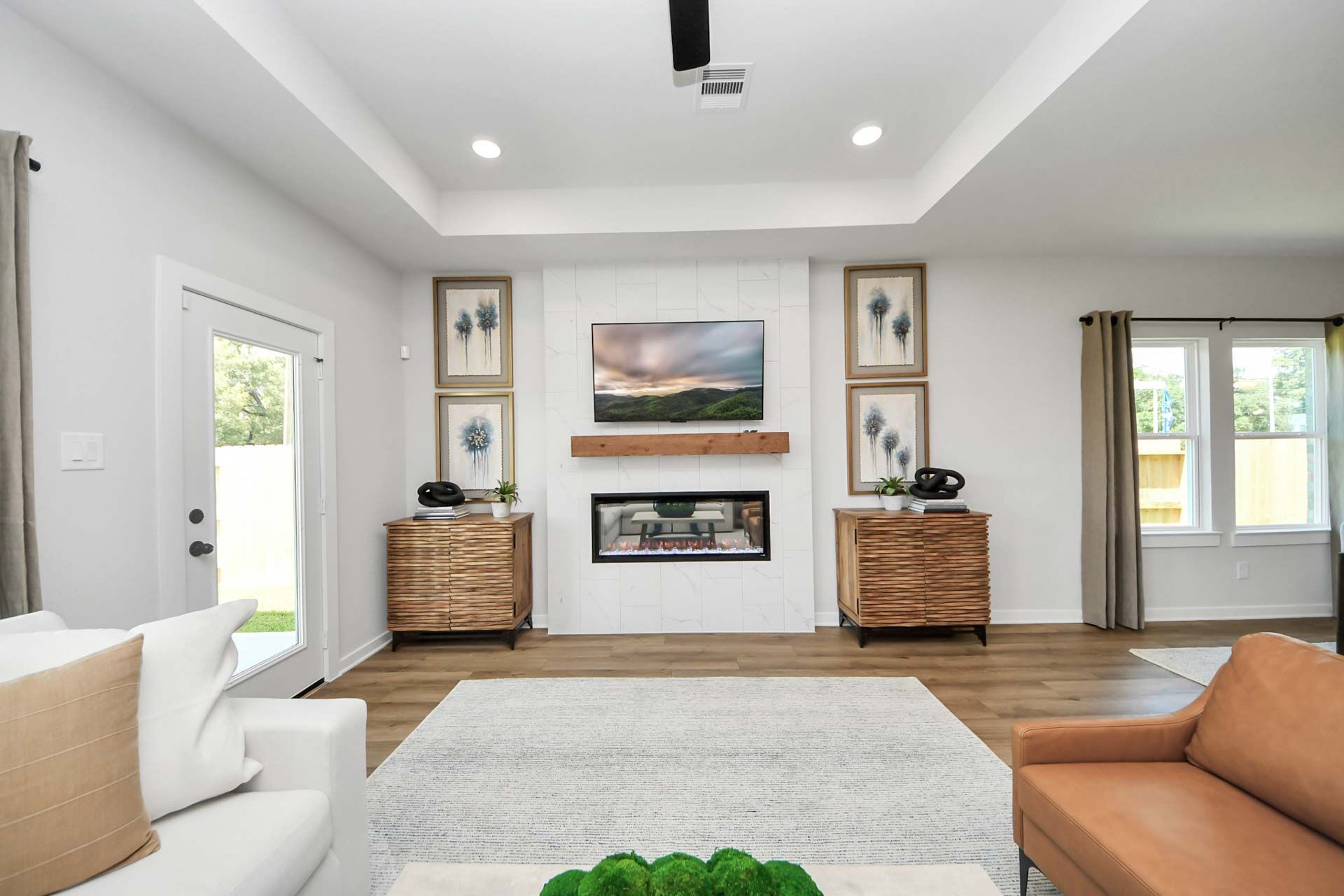 Modern living room at Enclave at Newport in Crosby, TX, featuring a tile fireplace, wood mantel, and stylish decor.