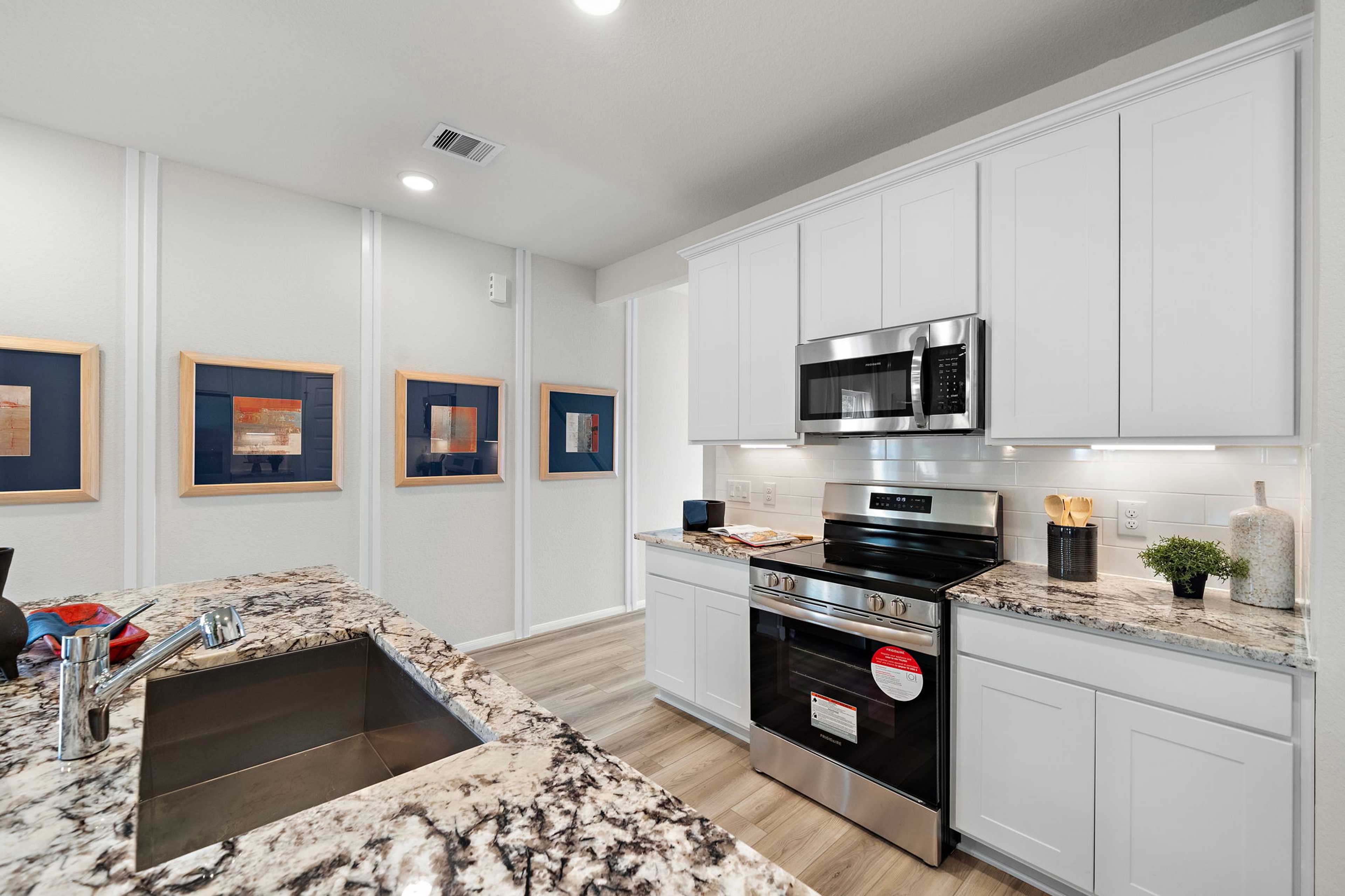 Spacious modern kitchen in Liberty Estates, Cleveland Texas by Davidson Homes with white shaker cabinets, granite island, stainless steel appliances