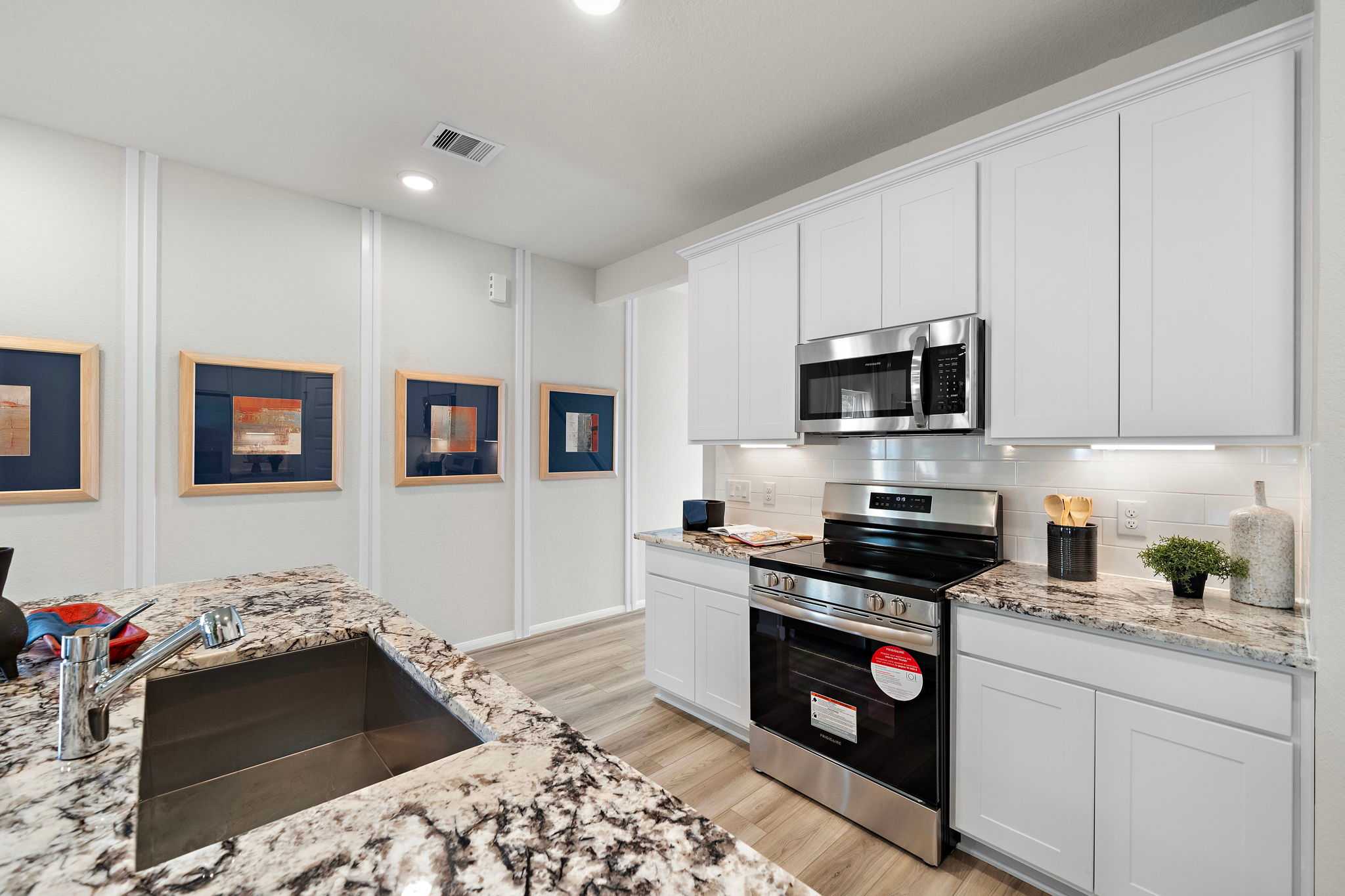 Spacious modern kitchen in Liberty Estates, Cleveland Texas by Davidson Homes with white shaker cabinets, granite island, stainless steel appliances