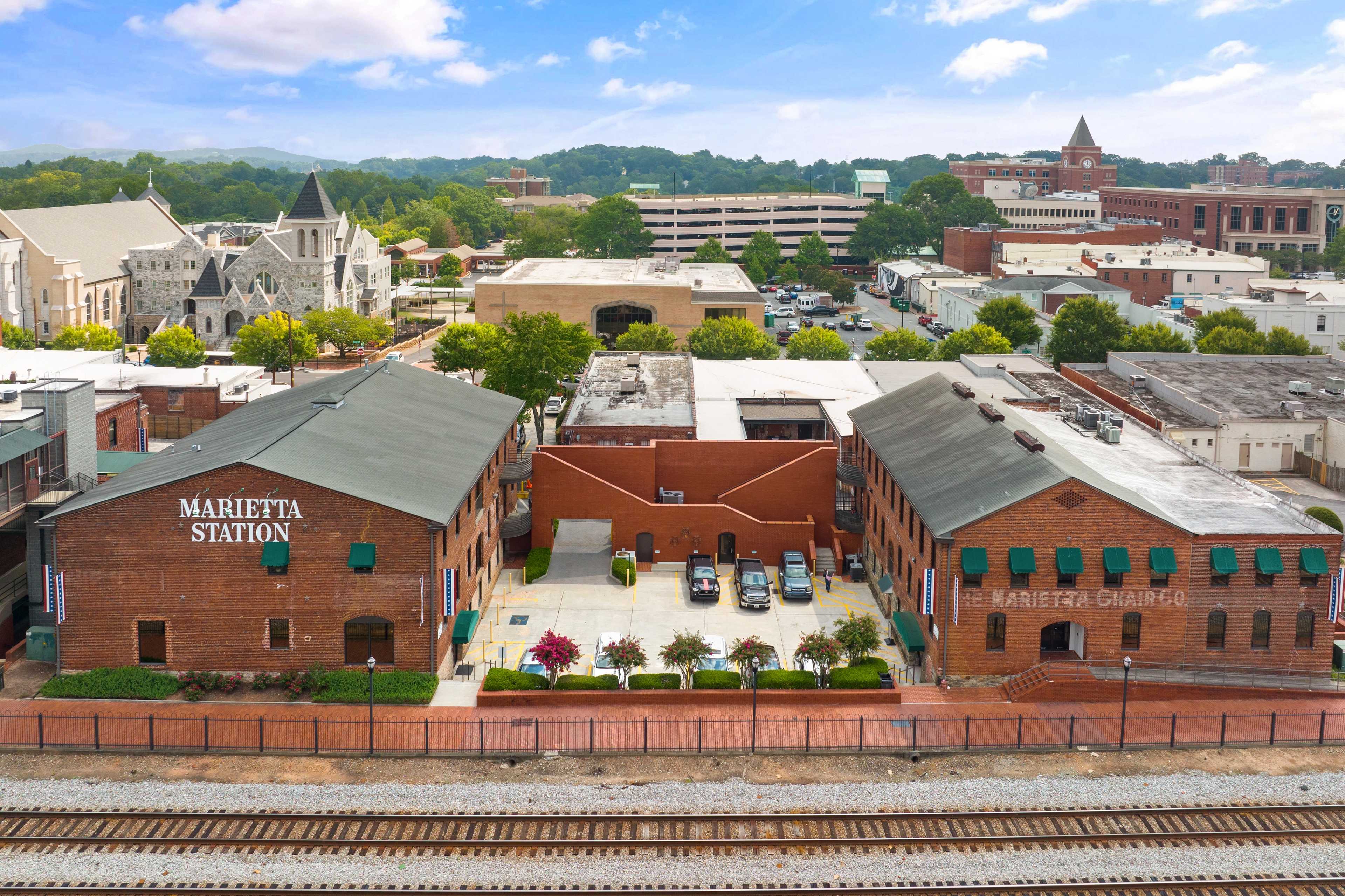 Aerial view of Marietta Station historic district in Marietta GA near Rosehill Townhomes with brick warehouses, green awnings, and railroad tracks